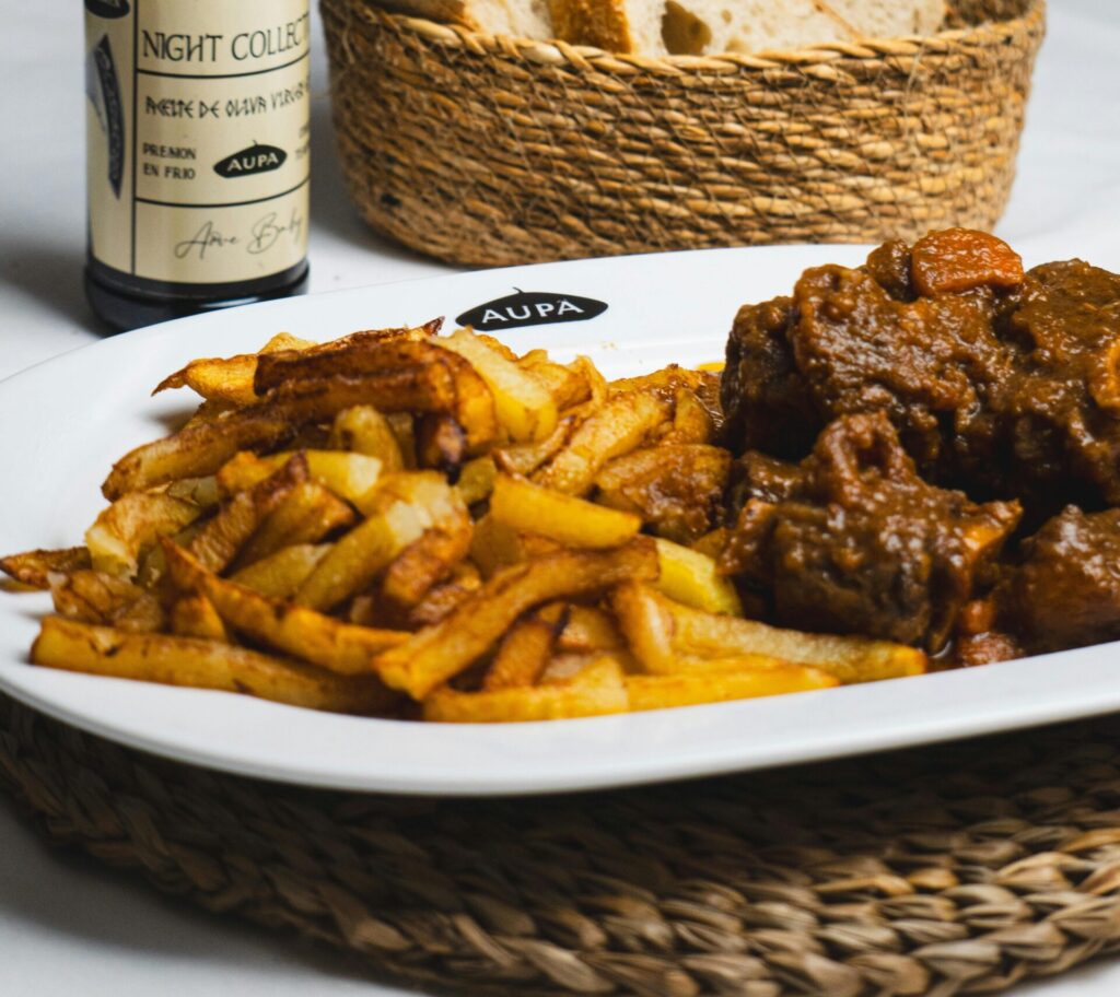Savor a classic Spanish meal with hearty stew, fries, and bread, paired with premium olive oil.