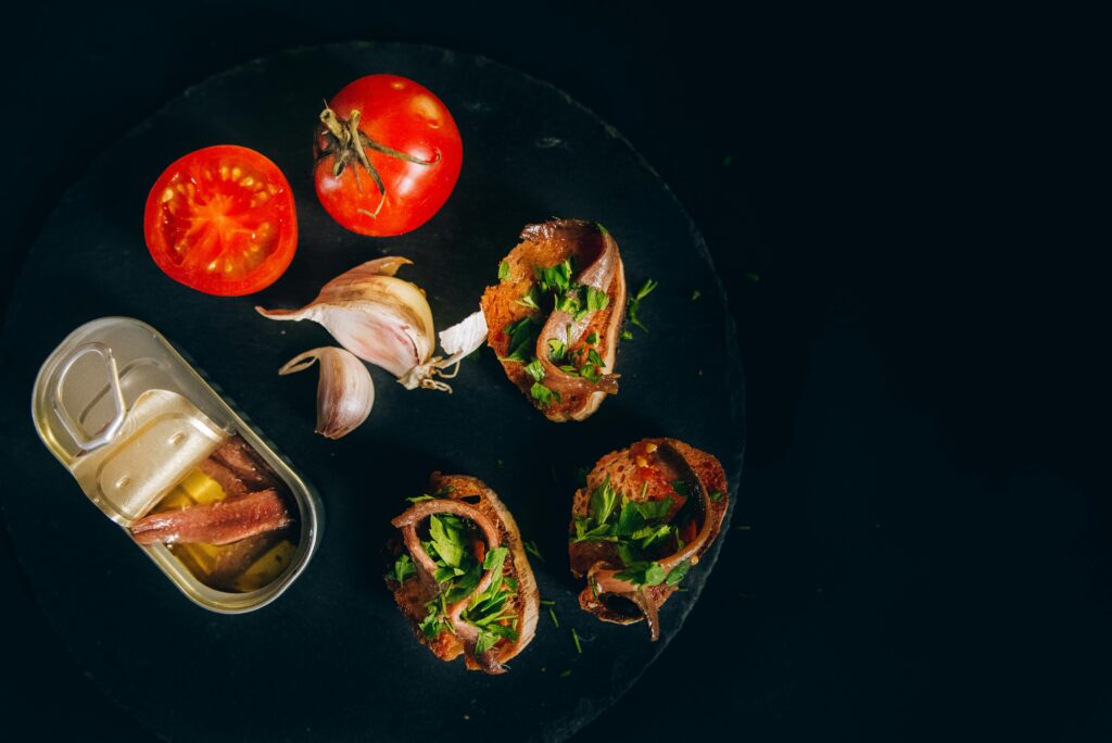 An appetizing top-down view of Catalan toast with anchovies, tomatoes, and garlic, ready to be savored.